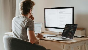 Man Sitting in Front of Three Computers