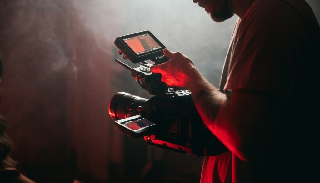 man in white t-shirt holding black video camera